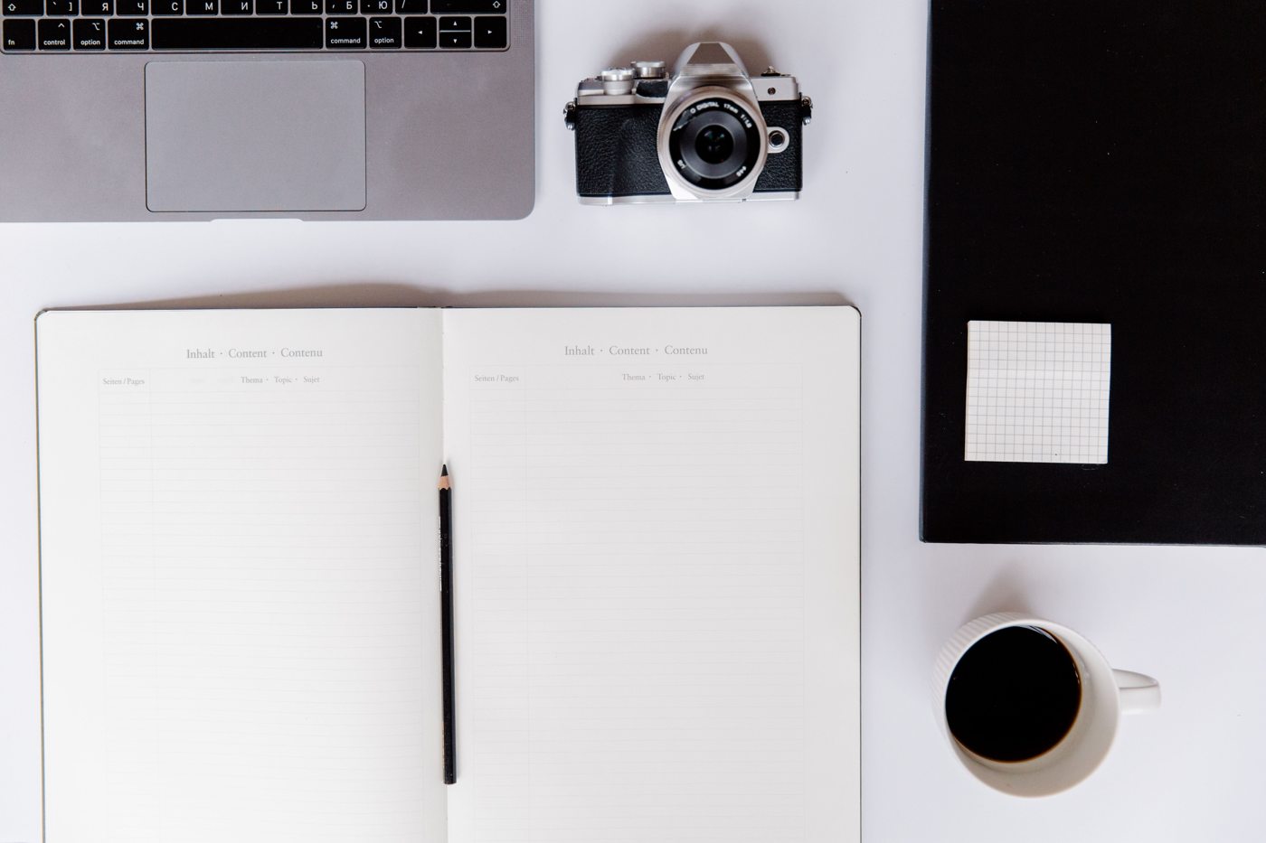 Notebook, camera, coffee, and laptop on a desk